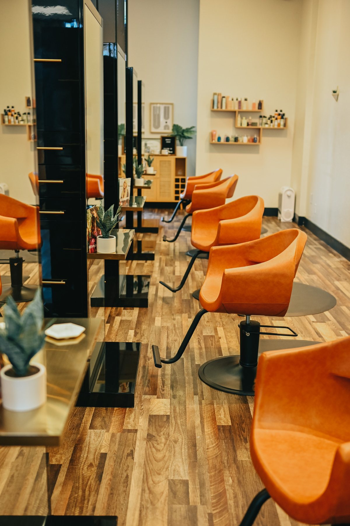 Inside Painted Mane, a boutique hair salon in downtown Walnut Creek with warm wood floors and signature orange styling chairs